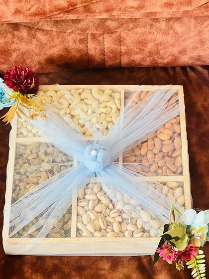 A top-down view of a large dry fruit gift box. The assortment includes cashews, almonds, raisins, and pistachios, making it a healthy and traditional gift for festivals.