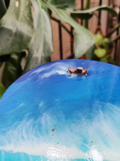 A close-up of the tiny boat sailing on the deep blue resin ocean, a small detail that adds a lot of character.