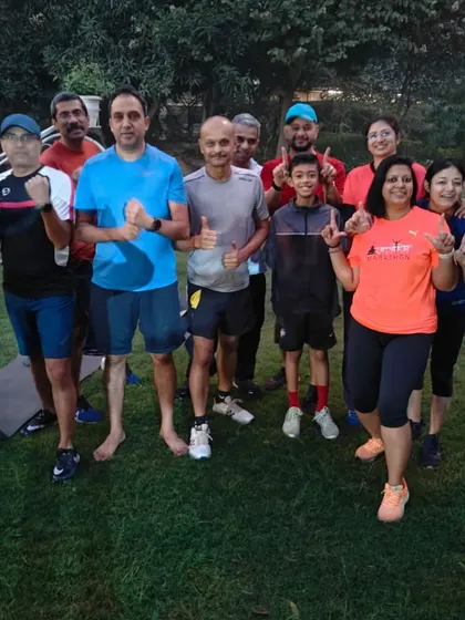 A group of our runners, including a young member, giving a thumbs up after a workout. We are a family-friendly community.