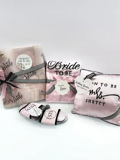 A set of personalized bridal gifts, including a "Bride to be" robe, a custom "Soon to be Mrs. Shetty" pillow, and matching slippers.
