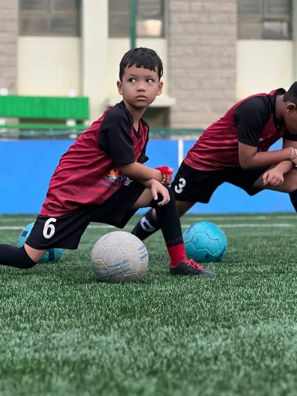 Waiting for the weekend matches be like... Two young players stretch and focus during a training session, getting their bodies and minds ready for competition.