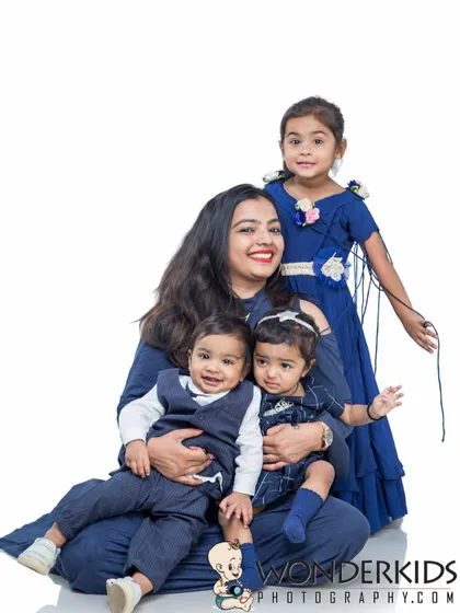 A beautiful family portrait of a mother with her three children. The coordinated blue outfits and their happy smiles create a harmonious and loving picture.