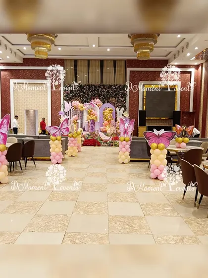 The butterfly theme extends throughout the venue with matching balloon pillars topped with large butterfly wings, lining the aisle and decorating guest tables.