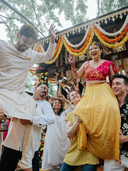 The bride and groom lifted on the shoulders of their friends and family, a moment of high energy and celebration during the Haldi festivities.