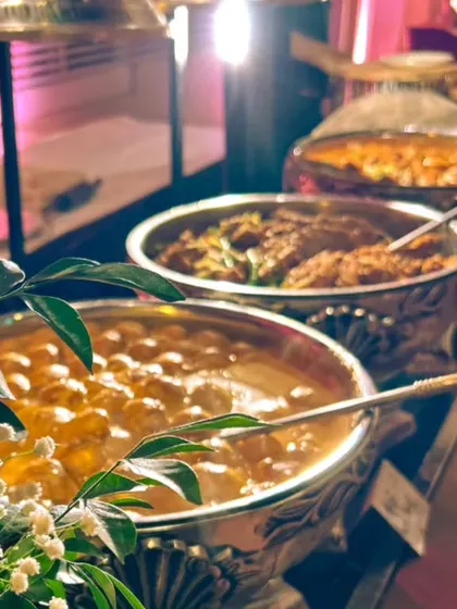 Dinner is served. A close-up of traditional Indian main courses like Kadai Paneer and Dal Makhani, simmering in elegant silver serving bowls, ready for the buffet.