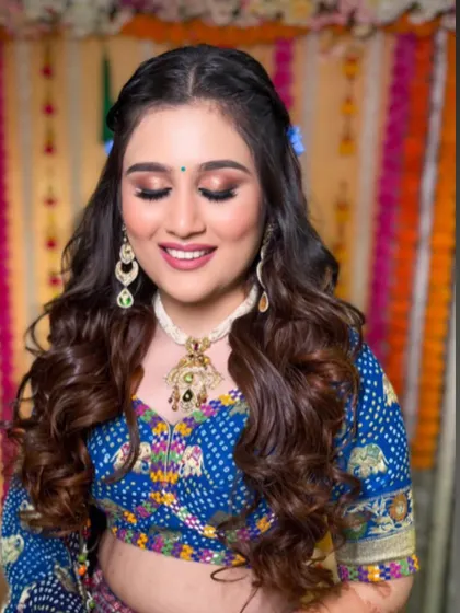 A close-up of the bride's happy face, her hair styled in soft curls with the vibrant blue flowers.