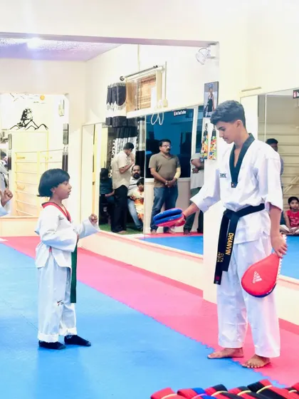 A senior student instructs a junior on the correct way to punch a target.