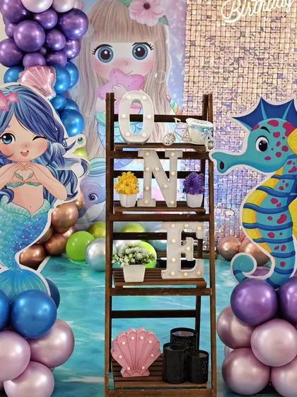 A decorative shelf with a light-up 'ONE' sign, surrounded by mermaid and seahorse cutout's.