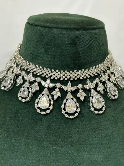 A close-up of an American diamond choker with teardrop pendants. The intricate design sparkles from every angle, making it a perfect rental for a night event.