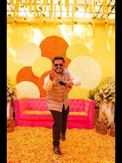 One, two, go! An action shot in front of a vibrant floral backdrop at a Haldi ceremony.