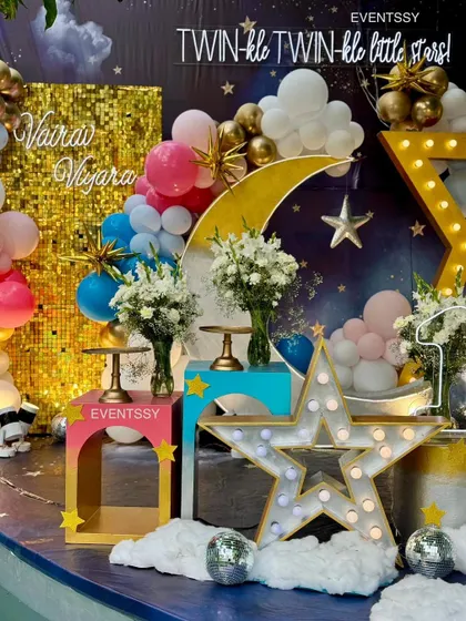 A detail shot showing the personalized names on the gold sequin wall and the fresh floral arrangements on the display stands.