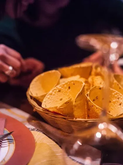A basket of crispy papad cones ready to be served at the table. This presentation style makes a familiar Indian snack a fun and interactive part of the meal.