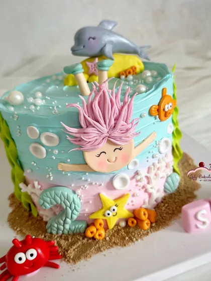 A delightful and playful "Under the Sea" cake, with a mermaid diving into the water, surrounded by a friendly dolphin and crab.