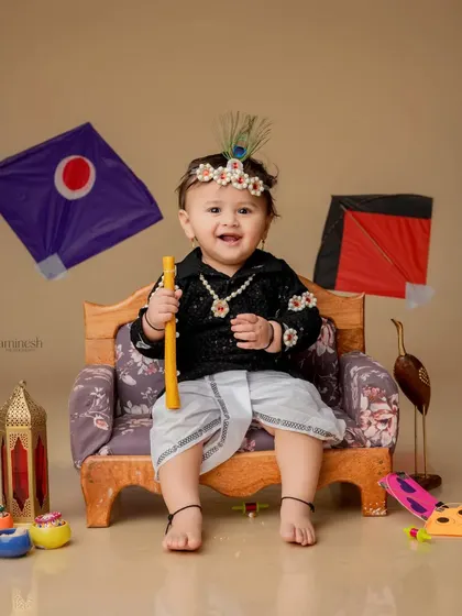 A smiling baby girl with a peacock feather in her sugar jewelry headband, ready to celebrate the festival. The props and outfit are all part of the package.
