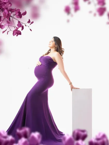 A regal portrait in a deep purple gown. The floral framing adds a soft, romantic touch to this elegant and colorful maternity photograph.