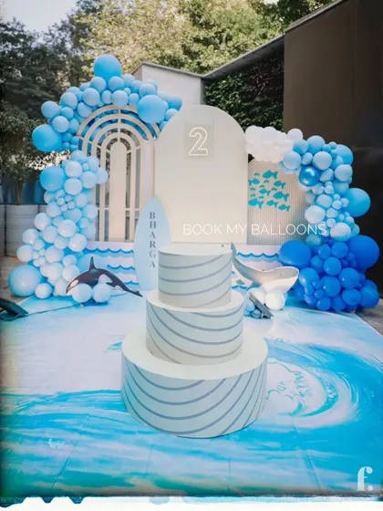 We created a cool and refreshing ocean wave theme for this second birthday party. The setup included a wave print floor mat, shades of blue balloons creating an arch, and whale cutouts to make it feel like a day at the sea.
