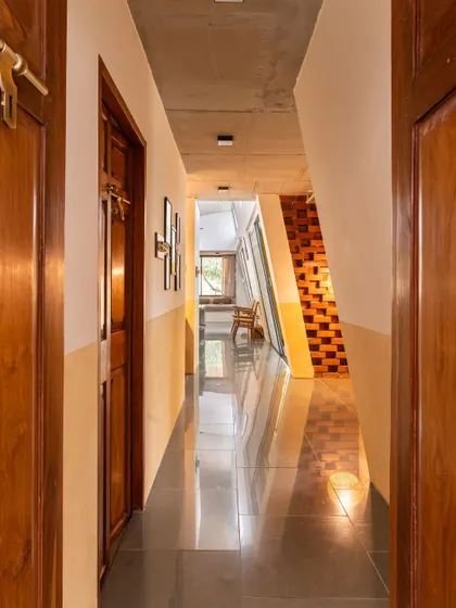 Looking down the service corridor of "Aamra," which compactly houses the wet areas of the home. This efficient planning, inspired by Agraharam layouts, maximizes the fluid, open living spaces.