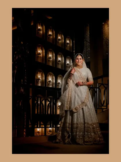 An elegant portrait of the bride at her Walima, set against a beautifully lit, arched wall.