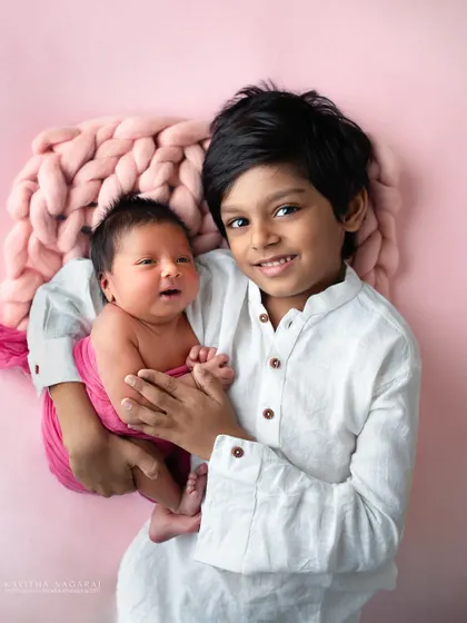 A proud big brother holds his three-week-new baby sister. The bond between siblings is so special, and capturing these early moments of love and protection is priceless.