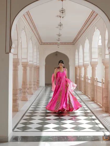 The bride twirling in a vibrant pink outfit in a beautiful palace corridor in Jaipur.