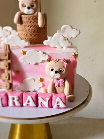 A close-up of the second teddy bear figurine, sitting sweetly amongst the edible name blocks.