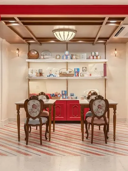 For the Parsi Dairy Farm renovation, I wanted to create a space that felt familiar yet fresh. This gifting zone, with its custom red cabinetry and floral upholstered chairs, is a cozy corner where customers can assemble hampers or enjoy a treat. It’s a perfect example of blending charming, old-world features with a clean, modern aesthetic.
