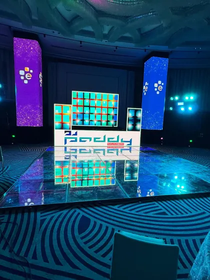A wide view of the setup for a corporate gig. The combination of a custom DJ booth, LED video pillars, and a reflective dance floor transforms the ballroom into a high-energy party zone.
