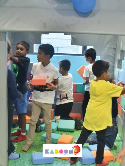 Teamwork in action! A group of boys works together inside a house made of soft play blocks, learning to share and build in a fun, collaborative environment.