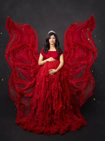 A powerful and angelic portrait. The dramatic red ruffled gown is styled to look like wings, creating a stunning and symbolic image of a mother's strength.