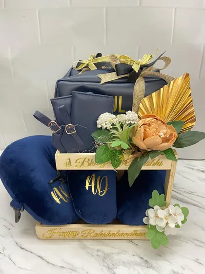 The complete travel-themed hamper for a couple, featuring personalized slippers, a travel pillow, and matching pouches, all beautifully arranged in a wooden stand.