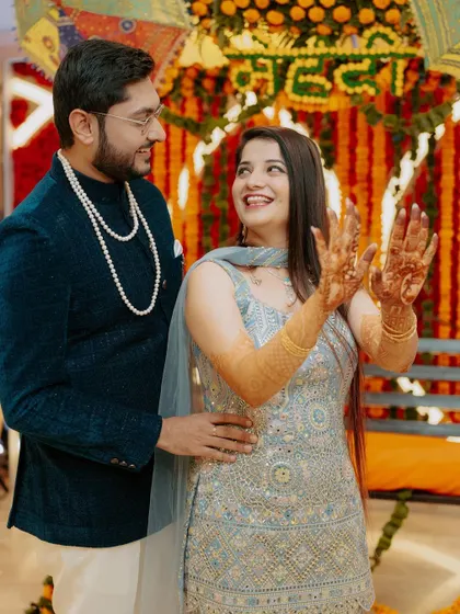 The bride joyfully shows off her fresh Mehendi to her partner. His admiring gaze and her bright smile make this a heartwarming candid shot.
