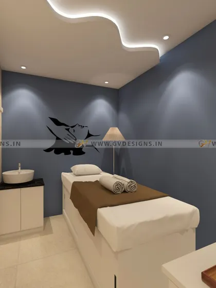A tranquil massage and treatment room designed for ultimate relaxation. The space features a soothing blue accent wall, soft cove lighting in the ceiling, a dedicated wash basin, and minimalist decor to create an uncluttered and peaceful sanctuary for clients.