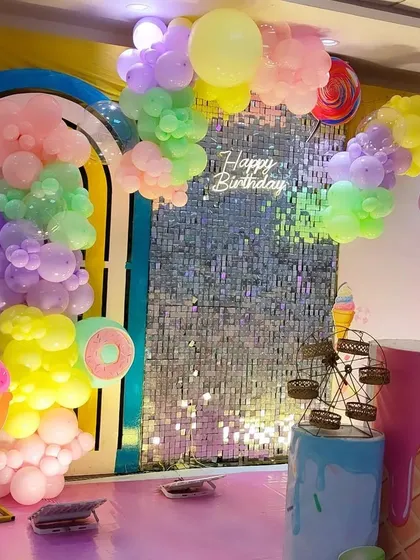 A different angle of the Candyland theme, showing the pastel balloon clouds and lollipop props. The sequin wall catches the light beautifully, adding a magical touch to the sweet-themed decoration.