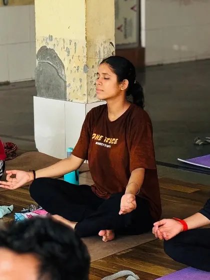 Finding peace amidst the practice. Three students are captured in a moment of quiet meditation, their calm expressions reflecting the internal state cultivated through yoga.