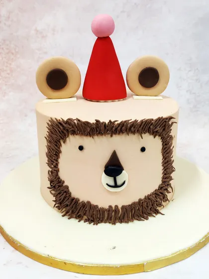 We love the simple charm of this minimalist lion face cake. With a friendly expression crafted from piped buttercream and a cute party hat, this design is a sweet and understated way to celebrate a little one's birthday.