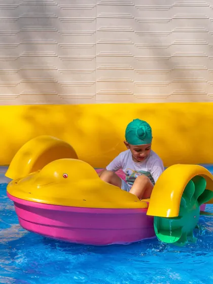 This little captain is expertly navigating his paddle boat around the pool.