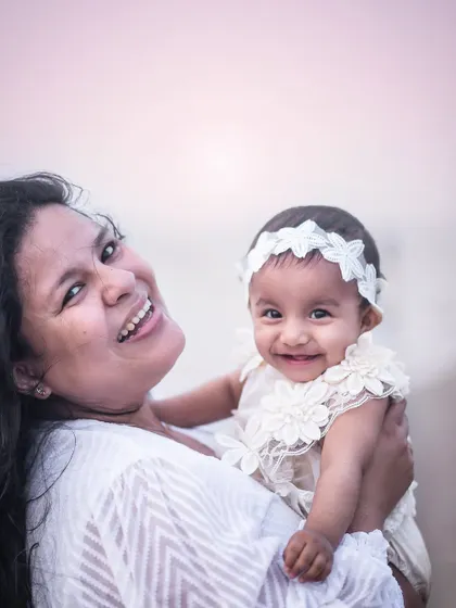 A beautiful, happy portrait of a mother and her baby girl at the beach. The genuine smiles and soft sunset light make this a truly precious memory.