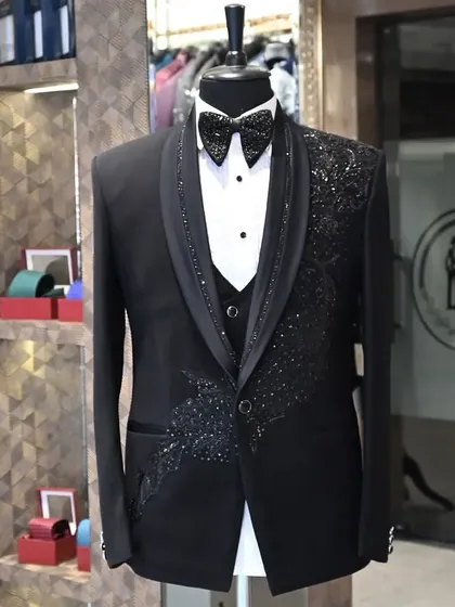 A black three-piece tuxedo with intricate, sparkling peacock feather embroidery. This is a perfect example of how I use detailed handwork to create a truly one-of-a-kind garment.
