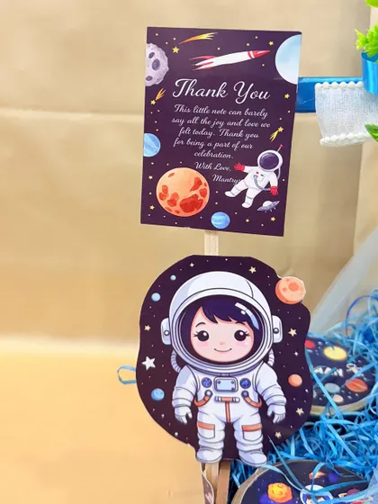 To the moon and back! A close-up of the custom thank you card and astronaut cutout for Ayaan's space-themed birthday hamper.