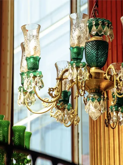 A close-up of our emerald green chandelier, showcasing the intricate glasswork and crystal details that adorn our space.