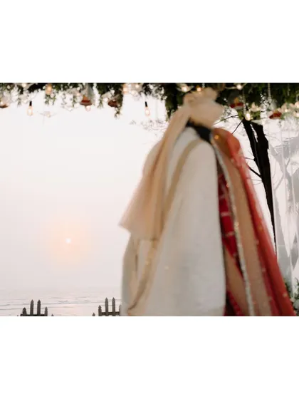 An artistic, blurry shot of the couple at their beachside mandap during sunset, creating a dreamy and romantic mood.