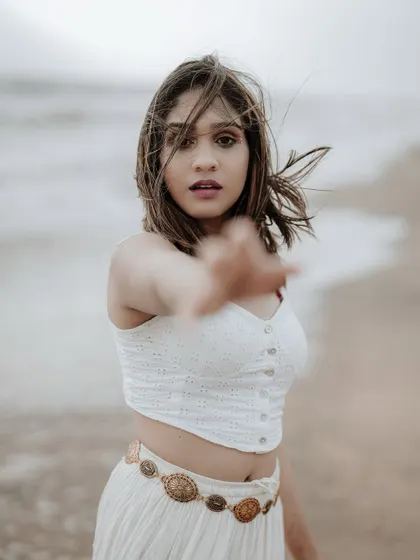 A captivating portrait with the model reaching towards the camera. The wind in her hair and the soft focus on the hand create a sense of intimacy and movement.