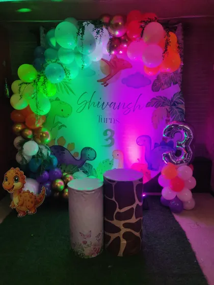 The same dinosaur theme, but this time under colorful party lights. This shows how the decor can be transformed with different lighting to create a fun, disco-like atmosphere for the kids.