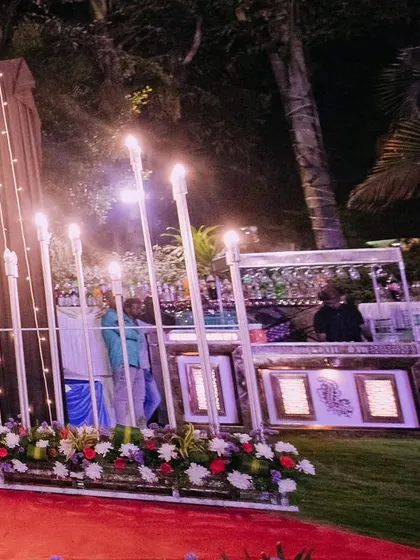 An outdoor bar setup for a reception, decorated with a floral base and modern lighting. Even functional areas are designed to be beautiful and match the event's theme.