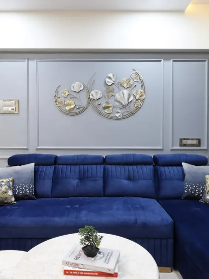 A wider view of the blue sectional sofa, showing how it anchors the living space. The nested coffee tables with marble tops and gold-finish bases complement the wall art and add to the room's modern aesthetic.