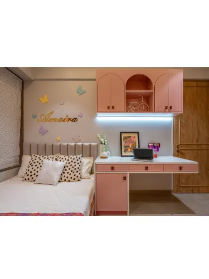 This bedroom features a built-in study desk with overhead storage, all in a charming pastel pink. The design is perfect for a young student, providing a dedicated space for creativity and learning.