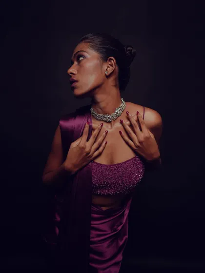 A full body shot showing the dramatic lighting and the rich color of the outfit. The makeup is designed to stand out even in low light conditions.