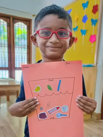 This smiling student shows his completed chart, correctly identifying objects that float and sink.