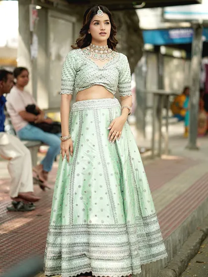 This pastel green lehenga offers a fresh and modern bridal or bridesmaid look, featuring subtle silver embroidery and a chic cropped blouse.