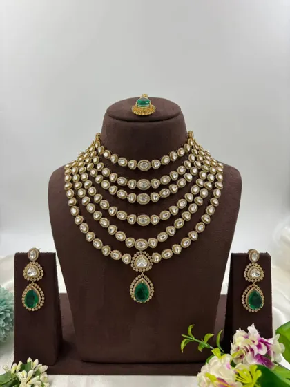 Our multi-layered Rani Haar sets are a bestseller. This piece showcases six layers of uncut Polki-style stones with a stunning emerald green pendant and matching earrings, offering a truly royal look for weddings and grand occasions.